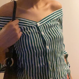 Randig snygg topp strl XS - Säljer en off shoulder med knappar (hade två band som armar i början som jag klippte bort) som är grön och vit. Sitter perfekt och har knytning i ärmarna. Frakt inräknat 