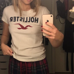 Hollister t-shirt - En vit Hollister t-shirt med blått och rött tryck på bröstet. Storlek M men sitter som en XS/S. Knappt använd:)🖤