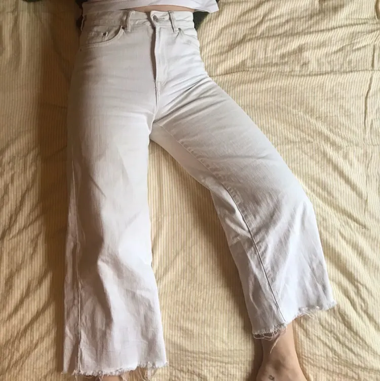 Croppade, vita, flared jeans från H&M. Fransiga vid nederkanten och slutar strax ovanför ankeln (168 cm). Köpta på H&M 2018 och i använt skick, därav priset. . Jeans & Byxor.