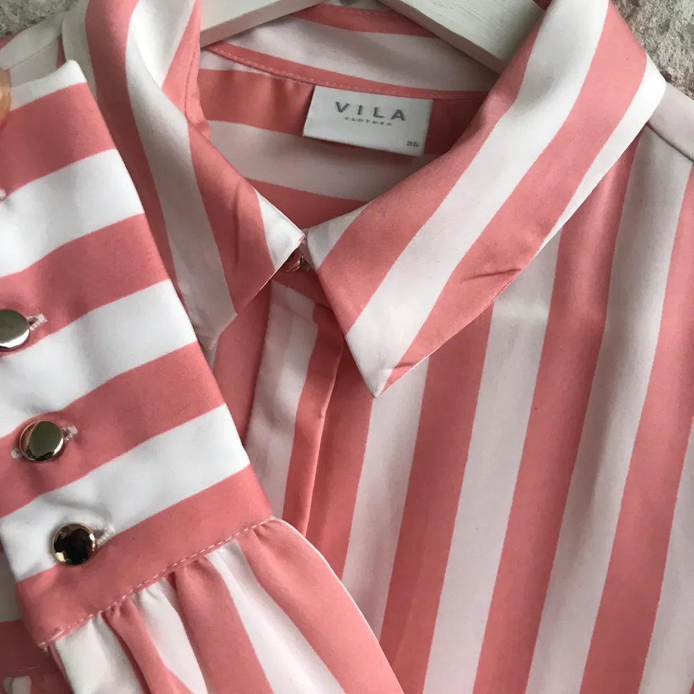 FINASTE rosa/vit randiga skjortan från Vila. Använd ca 2 gånger. Simpel och stilren men ändå unik. Sitter guldknappar på ärmarna och längst upp vid kragen (bild 3) - några av dem är skavda, inget man tänker på men kan skicka bild om så önskas💕💞🦋. Skjortor.