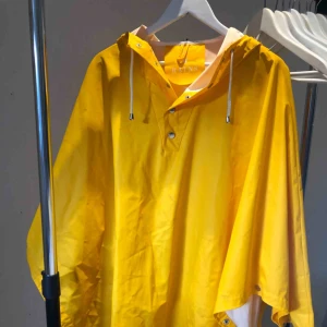  - Supersnygg gul regnjacka/regnponcho från märket Rains. Nypris 1049 kr. Sparsamt använd. Ponchomodellen är perfekt bland annat för cykelturer i regnet då den täcker knäna bra. Sannolikt storlek M men passar de flesta kroppsmodeller!