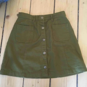  - Olivgrön kort jeanskjol. Knäppt hela vägen.