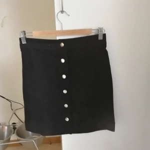  - Svart mockakjol med guldknappar i fram. Knappt använd pga fel storlek. 