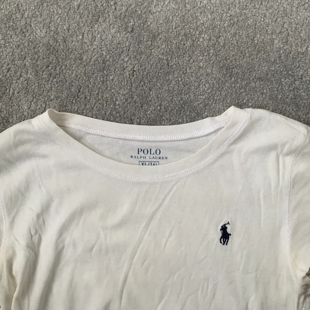 En vit Polo Ralph Lauren t-shirt med blått märke på ena sidan                    Köparen står för frakten . T-shirts.