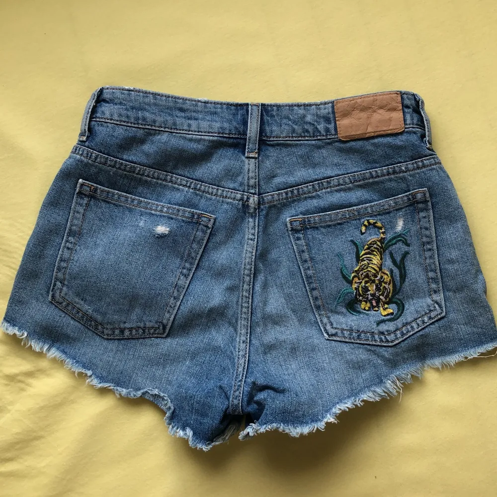 Säljer mina häftiga jeans short från H&M som jag har köpt men var för stora :( Storleken är 36 och den har en väldigt cool brodering av en tiger på bakfickan! I perfekt skick då den bara har blivit provad! . Shorts.