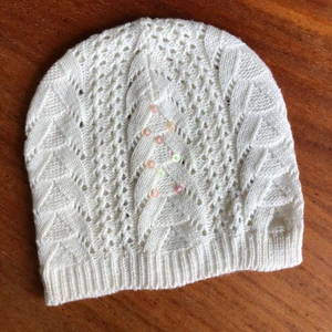 Stickad vit mössa - Stickad vit mössa med paljetter. Oanvänd. Kan hämtas i Malmö, osäker på exakt fraktkostnad.