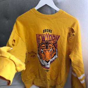 Gul collage tröja i stl. M - Säljer nu en stor trendfavorit. En gul collegetröja med revor från Gina i stl. M. Säljer den för 100kr. Frakt tillkommer💓