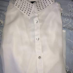 En vit skjorta med pärlor/paljetter på kragen. 