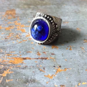  - ➿Förgylld ring med stor "sten" i mörk blått. Mystisk aura. Bra komplement till en mörkare outfit! Syns verkligen på handen. Okänt ursprung. Ca 18mm. Blandmetaller. Köpt 2hand, fint skick. Frakt: 7kr, skickas i vadderat kuvert.➿