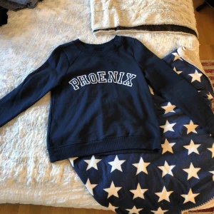  - En marinblå fin tröja som det står ”Phoenix” på.