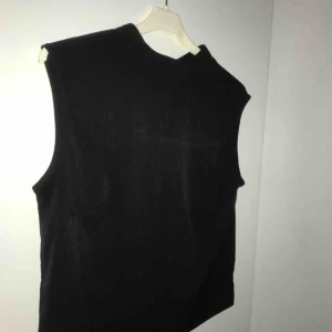  - En svart topp men lite krage, på baksidan finns en knapp till kragen. Silkes likande material. Vid frakt +55kr