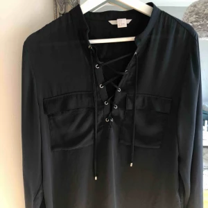  - Blus/skjorta med knytning. Sidenaktikt tunt material. Ser svart ut men den är mörk mörk blå. Nyskick! 