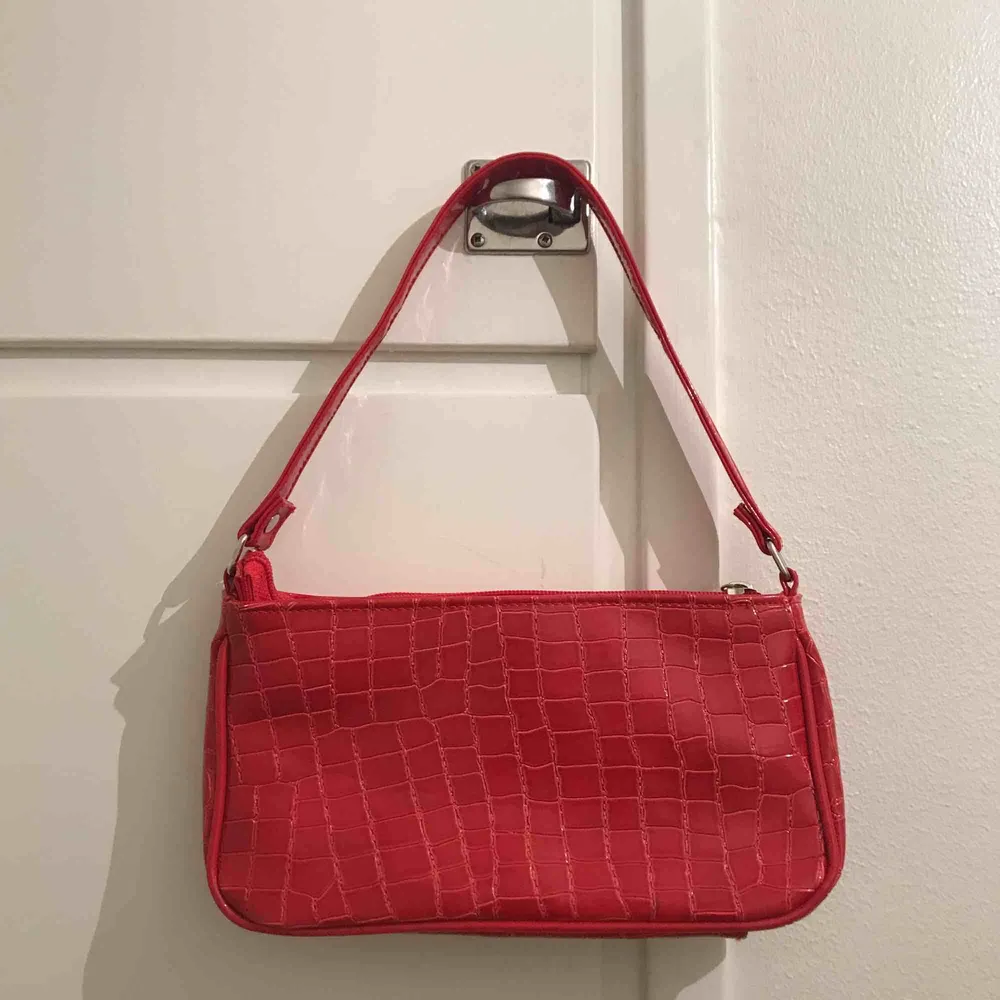 Super snygg röd lackväska med krokodil liknande mönster. Använd fåtal gångar, så i ett super bra skick! Kan mötas upp, men annars står köparen för frakten 🐉. Väskor.