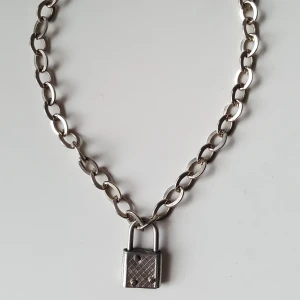  - Silverfärgat kedjehalsband med lås. Lite sprucken i ena hörnet på låset (se bild 2). Fraktkostnad blir 18kr.