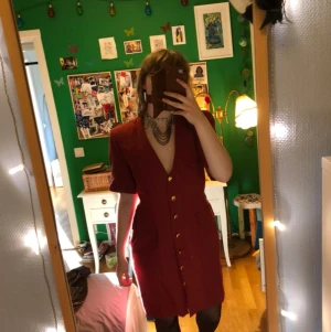Vintageklänning - Röd vintageklänning med guldiga knappar, axelvaddar och fickor ✨ Den har även stripes som kan knytas precis som på en knytblus (på bilden är de instoppade, om bild önskas skriv) ✨ Kan mötas upp eller skicka 