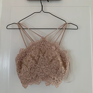 Unik topp - Unik topp hittad på secondhand i en fin nuderosa färg. Går bra att ha en bandlös bh under eller bara vika in banden. Sitter jättefint i ryggen oxå. Inga skador eller fläckar. Köparen står för fraktkostnad. 