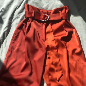 Vida Satin Byxor - Högmidjade satinbyxor med avtagbart skärp. Storlek 32 från hm. Är 170 och byxorna lägger sig fint över skorna. Original pris: 499kr💕 Frakt 49kr annars kan mötas upp i innerstan