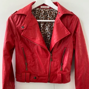 Skinnjacka imitation röd - ❤️Snygg skinnjacka (imitation), köpt i Spanien, använd fåtal gånger. Passar xs/s. Leopardtyg på insidan.