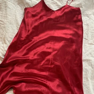 Satinklänning storlek L - Satinklänning i ca storlek L. Vinröd. Har en liten fläck av en bläckpenna (se bild 3) men det syns knappt. Står ingen storlek men uppskattar den att va L. Frakt tillkommer på 22-42kr