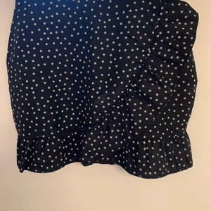 Svart kjol med vita prickar - Säljer denna svarta kjolen med vita prickar i storlek 38 från Pretty Little Thing. Passar mig som vanligtvis har Small. Har en volang på framsidan och knäpps med en dragkedja bak.
