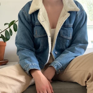 Croppad jeansjacka från Monki - Croppad jeansjacka från monki med ludd på insidan. Passar bra nu innan vintern. Ganska sparsamt använd men har fått lite fläckar på kragen, ska försöka få bort dem. Originalpris 600kr