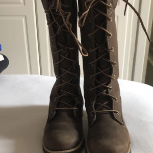 Timberland höga skor -  höga timberland skor i storlek 34.  Skorna har veck då de har används under EN vinter men annars är de i bra skick. Färgen är knsppt blekt och skorna är i bra skick för att ha använts under 2-3 månader!