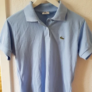  - Ljusblå äkta Lacoste piké, väldigt parsamt använd. Storlek xl, men är snarare en m. 
