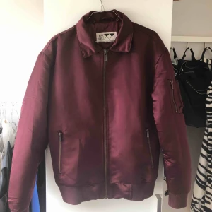  - Vinröd bomberjacka från Junkyard. Storlek XS men i herrmodell så en S/M i dam. Använd men i så gott som nyskick. Väldigt varm, går att använda som vinterjacka även i Sverige. Möts upp i Stockholm annars står köparen för frakt
