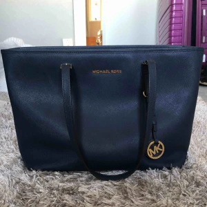 MK väska - Äkta Michael Kors väska i marinblått och gulddetaljer. Superfint skick då jag knappt använt den. Köpt för ca  3000kr för 3 år sedan.