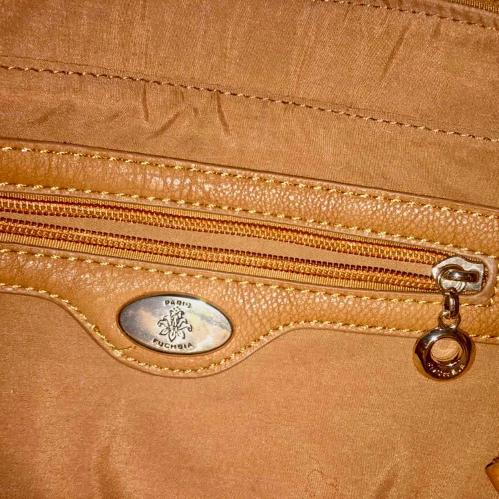 Jättefin brun läderväska (fejkläder) från Fuchsia med gulddetaljer, tre rymliga fack och ett litet. Med väskan kommer också en tillhörande axelrem. Aldrig använd så i mycket fint skick😊. Väskor.