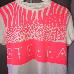 En cool T-shirt från Stella McCartneys kollektion med StellaSport. Har en dragkedja detalj på sidan, liten penna på kanten. Storlek S. Nypris ca 250kr