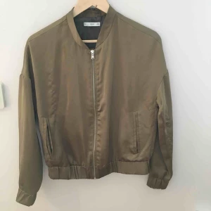 - Tunn olivgrön bomberjacka i glansigt material. 👌🏽(Några trådar som maskat sig lite, se bild tre.)