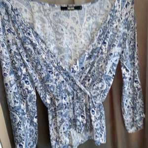  - Vit blus med blåa blommor på, en sval tröja som fungerar jättebra till sommaren. Köpt nyligen men aldrig använd.