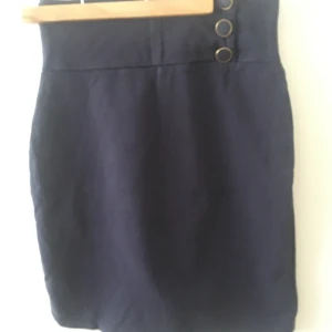 Kjol - Pennkjol i seglarställ med dekorationsknappar. Stl 38 men sitter som 36. 