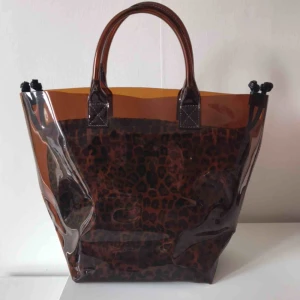  - Brun genomskinlig väska med tillhörande leopard fordring.