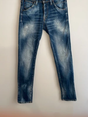 Jack and Jones jeans med tvättmärken - Säljer ett par Jack and Jones jeans i slimfit med snygga slitningar och tvättade effekter. Jeansen har fem fickor, dragkedjegylf och raka ben. Materialet är klassisk denim i bomull. Perfekta för en avslappnad och trendig look.