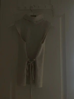 Beige ärmlös polotopp - Trendig beige ärmlös polotopp med lite finare material aldrig använd. hade nog sagt att den är lite begie vit