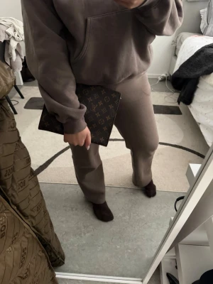  kuvertväska - Säljer en klassisk brun kuvertväska i  beige. Väskan har en smidig dragkedja upptill och är tillverkad i tåligt canvasmaterial med läderdetaljer. Perfekt storlek för det viktigaste och ger en lyxig touch till din outfit.