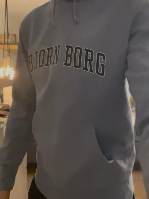 Blå hoodie från Björn Borg - Snygg blå hoodie från Björn Borg. Perfekt för en avslappnad och sportig stil. Mjuk bomullsblandning och ribbade muddar vid ärmar och midja. Knappt använd storlek m