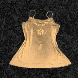 Beige linnetopp från Funky Fig - Säljer en beige linnetopp från Funky Fig med tunna axelband och trycket 'FUNKY FIG' på ryggen. Toppen har ett diskret leopardmönster och är tillverkad i ett mjukt material som känns skönt mot huden. Perfekt för dig som gillar en enkel men cool stil.