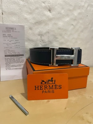 Blått skärp med silverdetalj - Snyggt blått skärp med stor silverfärgad spänne. Skärpet har vita kontrastsömmar och kommer i original orange box. Perfekt accessoar för att lyfta din outfit.