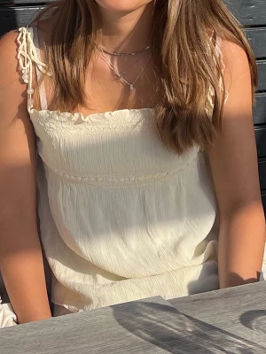 Ljusgul somrig topp - Ljusgul somrig topp från mango i storlek L. Skulle säga att den även passar M, vilket jag brukar ha. Fina detaljer på framsidan samt pärlor på axelbanden. Luftigt material på toppen. Passar väldigt bra på sommaren när man har lite färg!  Obs: har en liten rosa fläck på framsidan som inte syns så mycket. Fläcken är med på alla bilder men syns inte, se sista bilden för att urskilja fläcken.