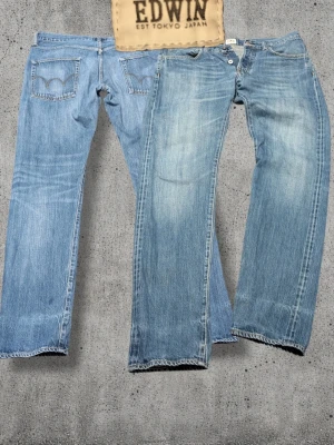 Ljusblå Edwin selvedge jeans - Säljer ett par ljusblå Edwin jeans med klassisk rak passform och tydlig selvedge-detalj vid benslutet. Jeansen har fem fickor, snygg slitning framtill och bakfickor med broderad båge. Tillverkade i robust denim, perfekta för en avslappnad streetstil.