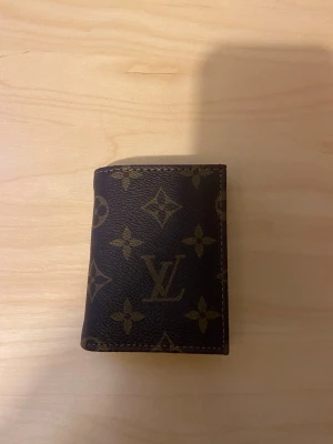  monogram plånbok - Snygg brun plånbok i klassiskt monogrammönster och blommor. Tillverkad i tåligt läder med guldfärgade detaljer. Perfekt storlek för kort och sedlar, och en riktig ikon för dig som gillar lyxiga accessoarer.