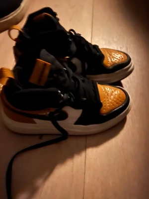 Svart och orangea high sneakers - Snygga high sneakers i svart, orange och vitt med klassisk siluett. Skorna har svart snörning, vit sula och detaljer i läderimitation. Perfekta för dig som vill sticka ut med färg och stil.