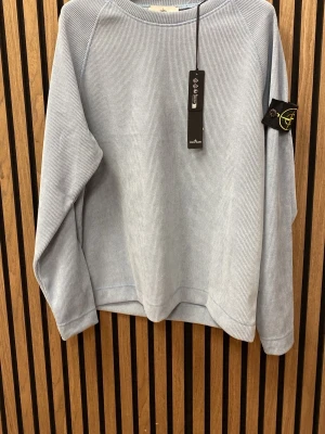 Ljusblå stickad tröja  - Snygg ljusblå stickad tröja med klassisk patch på ärmen. Tröjan har rund halsringning, ribbstickad struktur och långa ärmar. Perfekt för dig som gillar stilrena och trendiga plagg i mjukt material.