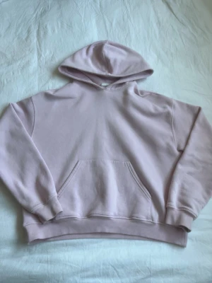 Ljuslila hoodie med magficka - En stilren ljuslila hoodie med klassisk huva och stor magficka framtill. Hoodien har ribbade muddar vid ärmslut och nederkant. Perfekt för en avslappnad och trendig look. Materialet känns mjukt och bekvämt mot huden.