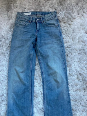 Blå raka jeans från Zara  - Säljer ett par klassiska blå jeans från Zara med rak passform och fem fickor. Jeansen har en ljus tvätt och normal midja, perfekta för en avslappnad stil. Tillverkade i bomull med en tidlös look och subtila slitningar.