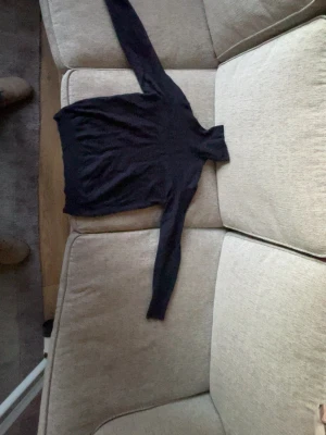 Mörkblå polotröja från Riley - Mysig mörkblå stickad merinoull polotröja från Riley  med lång ärm och ribbade muddar. Tröjan har en klassisk passform och är tillverkad i ett mjukt, ulligt material. Perfekt för kalla dagar och enkel att matcha med olika outfits. Storleken är L i barnstorlek och passar 158-168!   Pga litet hål i armhålan (omärkbart) sänks priset enormt! Priset är diskutabelt 