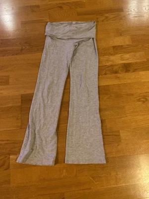 Gråa bootcut leggings - Säljer ett par ljusgrå leggings med bootcut-ben och bred linning. Mjukt och stretchigt material som sitter skönt på kroppen. Perfekta för en avslappnad och trendig look.